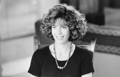 a black and white photo of a woman sitting in a chair with a necklace on her neck