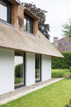 a house with thatched roof and windows on the grass field next to it's lawn