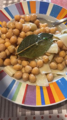 a plate filled with beans and cheese on top of a colorful table cloth next to a spoon