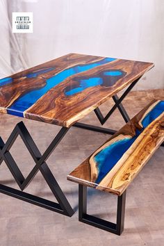 a table and bench made out of wood with blue paint on the top, in front of a white wall