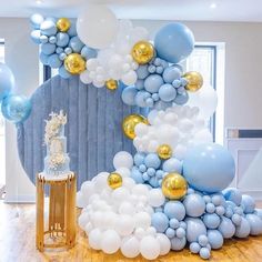 a large balloon arch with blue and gold balloons on it in the middle of a room