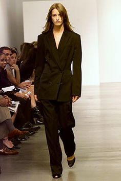 a model walks down the runway in a black suit and matching shoes with other people