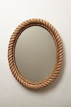 a round rope mirror hanging on the side of a wall next to a white wall