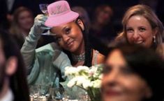 a woman wearing a pink hat sitting at a table with other people in the background