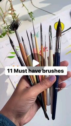 a person holding a bunch of brushes in their hand with the words 11 must have brushes