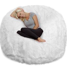 a woman sitting on top of a fluffy white bean bag chair with her legs crossed