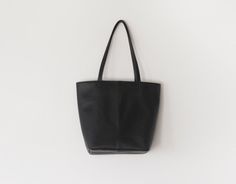 "This tote bag features soft black leather and navy interior lining. This bag is small. Carry your phone, a wallet, keys and other small items in this bag. Details: -Dimensions: 11\" length (top to bottom), 14.5\" top width and 9.5\" bottom width (side to side), 5\" depth, 9.5\" X 5\" base (bottom) -Each shoulder strap measures approximately 23\" full length -Soft black leather -Cotton interior lining - color can be customized (shown in the picture is burgundy) -One Internal pocket Because each Black Soft Leather Bucket Bag For Daily Use, Modern Medium Shoulder Bag For Daily Use, Modern Medium Satchel For Daily Use, Versatile Black Bag With Card Slots, Versatile Black Bag With Interior Card Slots, Versatile Black Bags With Interior Card Slots, Everyday Medium Shoulder Bag With Removable Pouch, Black Satchel For Daily Use With Interior Card Slots, Medium Black Bag With Removable Pouch