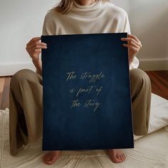 a woman sitting on the floor holding up a sign that says, the struggle is part of the story