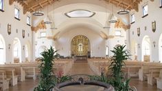 the inside of a church with benches and plants