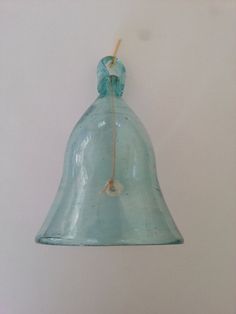 a glass bell hanging from the side of a wall with a string attached to it