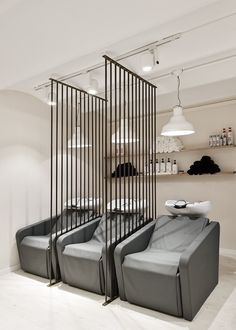 two gray chairs sitting next to each other in front of a wall with black bars