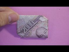 an origami money bill with a toothbrush sticking out of it on a pink background