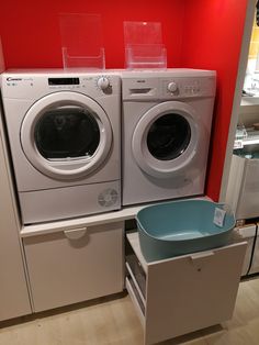 two washers and a dryer in a room with red walls, one is empty