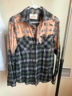 an orange and black plaid shirt hanging on a clothes rack next to a hanger