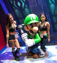 two women standing next to a mario bros character