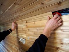 a person is working on a wood paneled wall