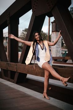 a woman is posing on a bridge with her arms out and legs spread wide open