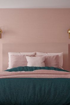 a bed with pink and teal colored linens on the headboard is shown