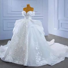 a white wedding dress on a mannequin in front of a wall and floor