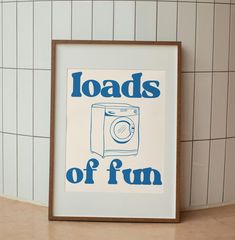 a framed poster with the words loads of fun in blue on a white tiled wall