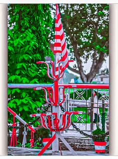 a red and white striped umbrella sitting on top of a metal pole next to trees