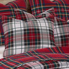 a bed with red and green plaid pillows on it