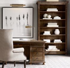 a desk with a chair, bookshelf and vases on it in front of a framed photograph