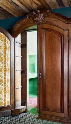 an open wooden door in a room with green walls and patterned rugs on the floor