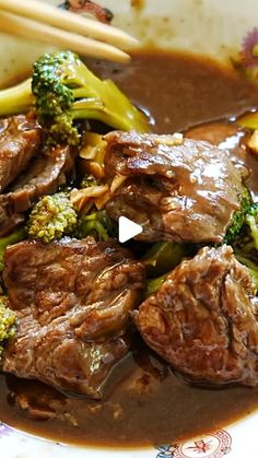 beef and broccoli in gravy on a plate with chopsticks