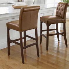 two brown leather bar stools in a white kitchen