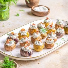 small appetizers are arranged on a white platter with green garnishes