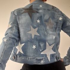 a woman wearing a jean jacket with stars painted on the front and back of it