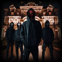 three men in black hoodies and masks standing in front of a house at night