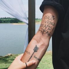 two people holding hands with tattoos on their arms that say reality is wrong, dreams are real