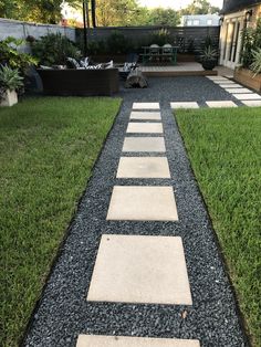 a walkway made out of stepping stones leads to a patio area with grass and plants