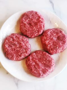 four hamburger patties on a white plate