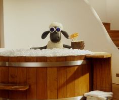 a stuffed sheep sitting in a wooden bath tub