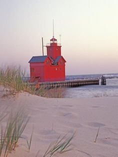 a red lighthouse sitting on top of a sandy beach