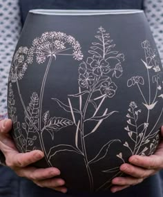 a person holding a vase with flowers painted on it