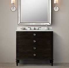 a bathroom vanity with a mirror above it and two lights on the wall next to it