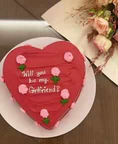 a red heart shaped cake with roses on it and the words will you be my girlfriend?