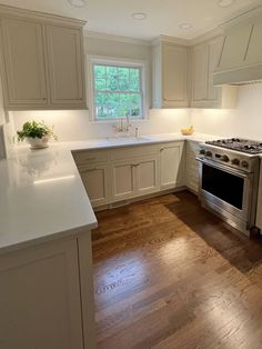 an empty kitchen with white cabinets and wood floors