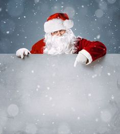 a santa clause holding a sign with snow falling on it and looking at the camera