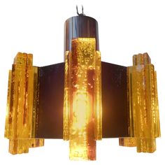 a chandelier made out of glass and metal with yellow lights on each side