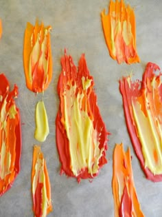 orange and yellow pieces of paint on top of a baking sheet with spatulas