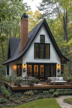 a white house in the woods with lots of trees and plants on it's deck