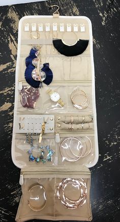 the contents of a travel jewelry bag are neatly organized on a black countertop, including bracelets, rings and necklaces