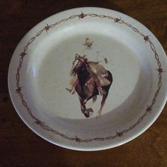 a plate with barbed wire around it and a horse painted on the inside of it