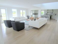 a living room filled with white furniture and wooden floors