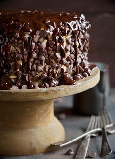 a cake with chocolate frosting and sprinkles sitting on top of a wooden plate